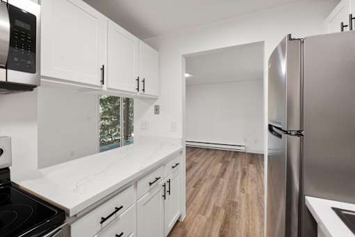 A modern kitchen with white cabinets and a stainless steel refrigerator.