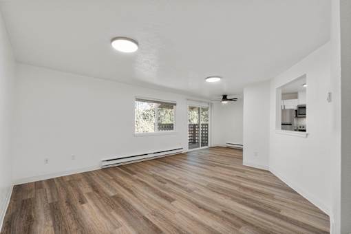 A spacious room with wooden flooring and white walls.