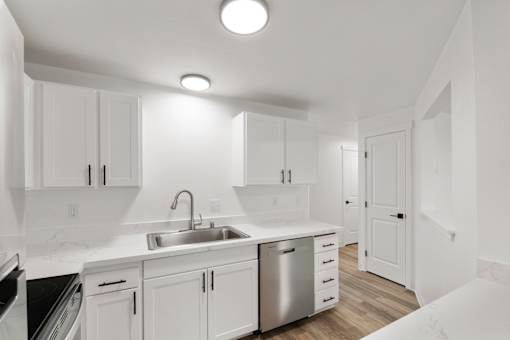A modern kitchen with white cabinets and stainless steel appliances.