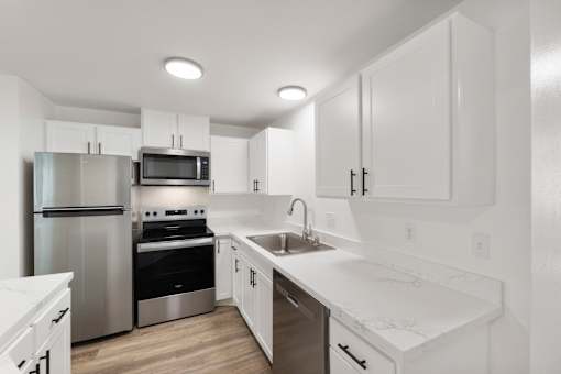 A modern kitchen with white cabinets and stainless steel appliances.