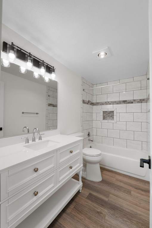 A white bathroom with a sink, mirror, and toilet.