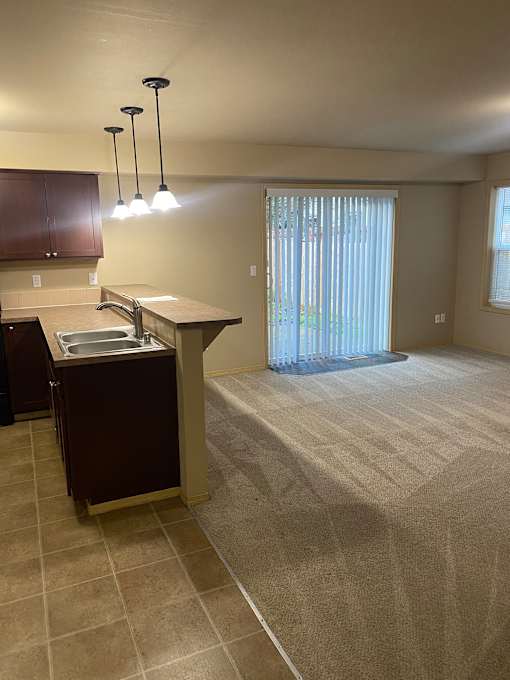 A kitchen with a brown cabinet and a window with blinds.