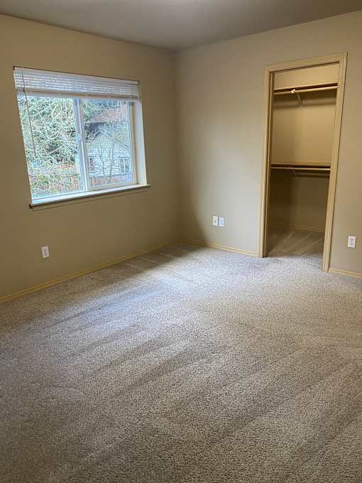A window with a view of a building outside is in a room with a textured wall.