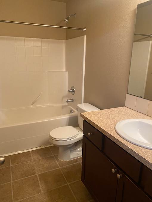 A white toilet is mounted on a brown wall in a bathroom.