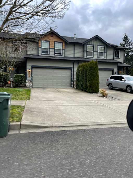 A grey house with a grey car parked in front.