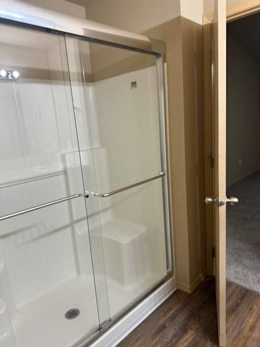 A white shower with a glass door and a silver handle.