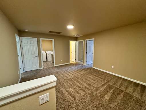 A spacious room with carpeted floor and white trim.