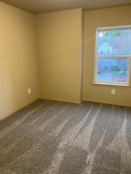 A room with a window and a carpeted wall.