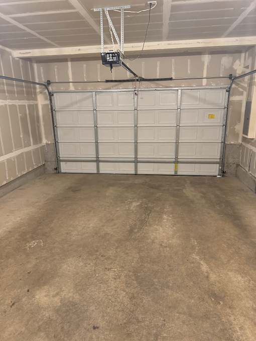 A white door with a yellow label is in a concrete room.