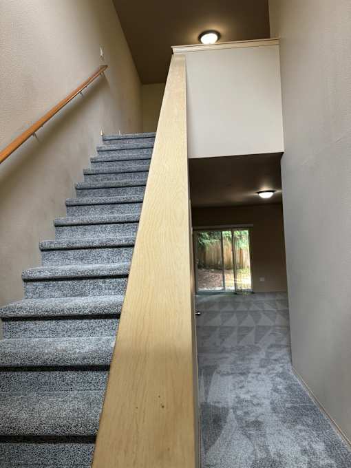 A room with a long wooden ledge and a wall with a grey pattern.