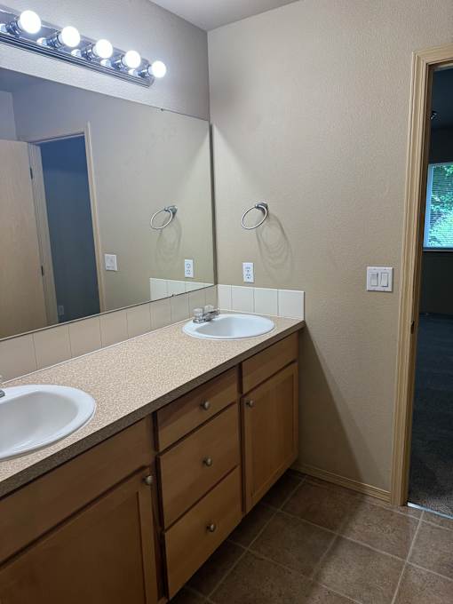 A bathroom with a mirror, light, and sink.