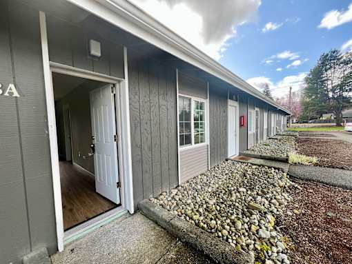 A grey building with a white door is shown.