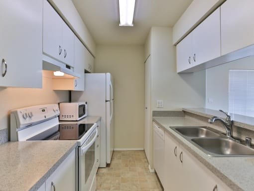 Kitchen with white cabinets and appliances and a sink  at Charbonneau Apartments in Seattle, WA 98101