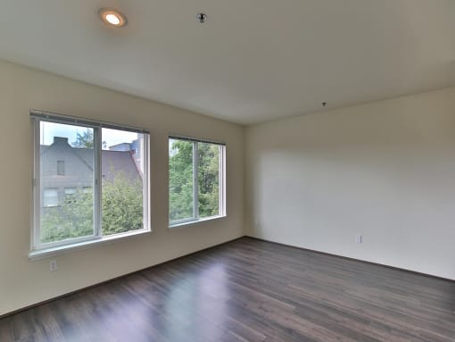 Empty living room with wood floors and large windows  at Charbonneau Apartments in Seattle, WA 98101