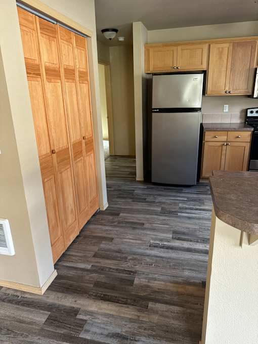 A kitchen with a stainless steel refrigerator and wooden cabinets.