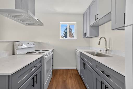 A kitchen with a white counter top and grey cabinets.