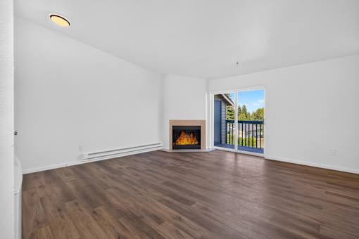 A room with a fireplace and a view of the outdoors through a sliding glass door.