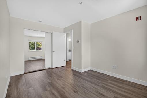 Bedroom at Ridgeline Apartments in Everett, WA with wood plank flooring, beige walls, and a mirrored closet door.