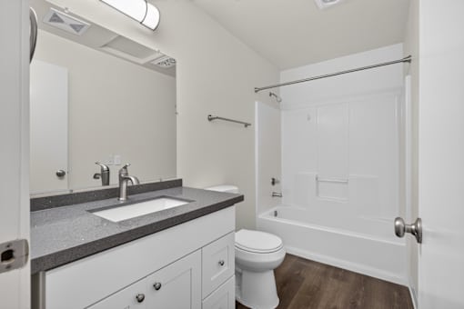 A bathroom with a toilet, sink, and mirror.