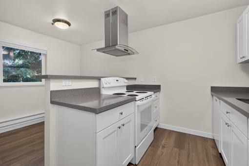 A kitchen with white cabinets and a stove top oven.
