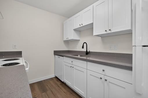 A kitchen with white cabinets and a grey countertop.