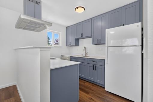 A kitchen with white appliances and grey cabinets.