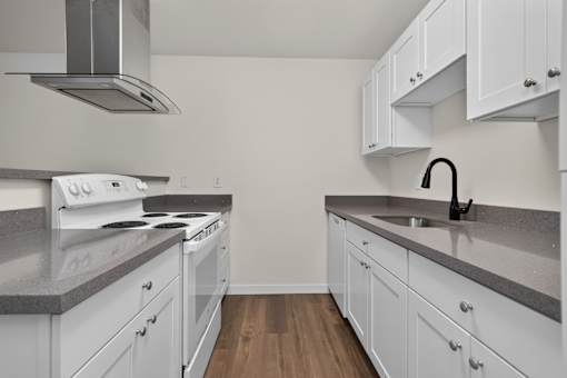 A kitchen with white cabinets and a stove top oven.