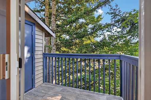 A balcony with a blue door and a wooden railing.