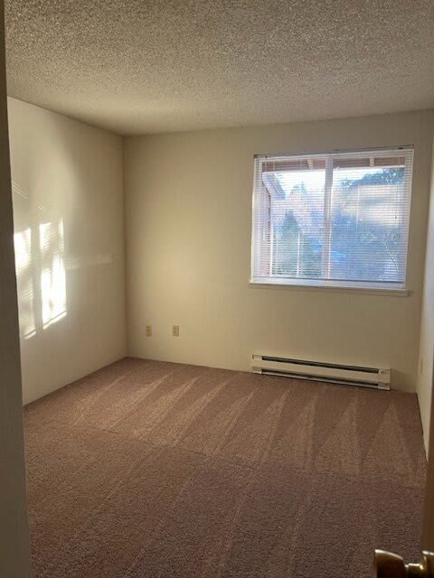 A room with a carpeted floor and a window with blinds.