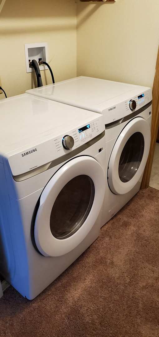 A pair of Samsung front loading washing machines in a laundry room.