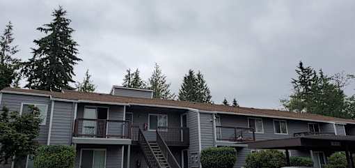 A grey apartment building with a balcony and stairs leading to the second floor.