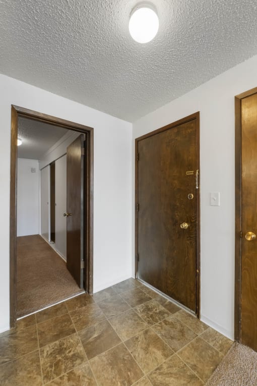 an empty room with two doors and a hallway with a door to a closet