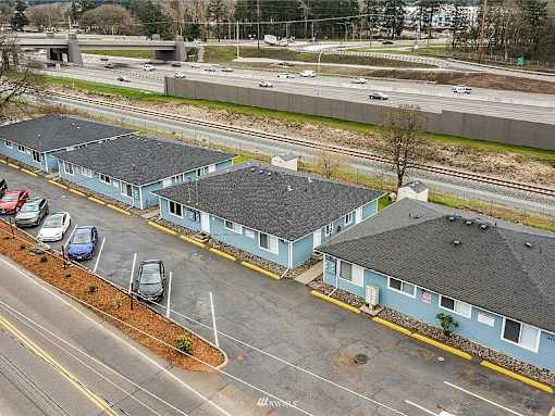 A parking lot with a few cars and a building with a yellow line in front of it.