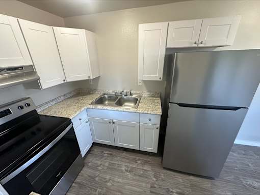 A kitchen with a stainless steel refrigerator, sink, and oven.