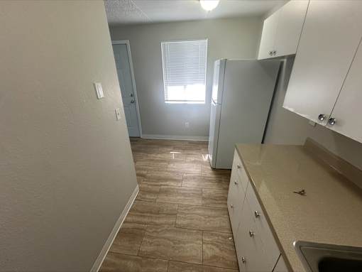 A kitchen with a refrigerator, sink, and cabinets.