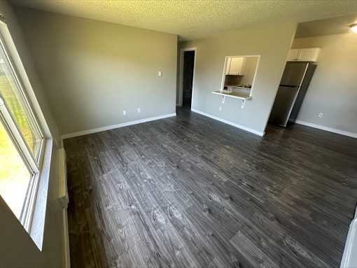 A room with wooden flooring and a window on the left side.