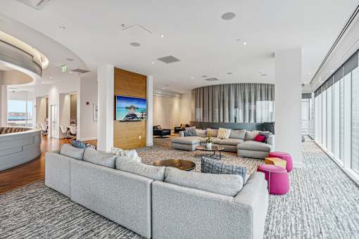 A modern living room with a grey sofa and a large screen on the wall.