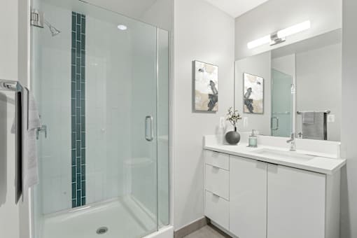 A white bathroom with a glass shower and a white vanity.