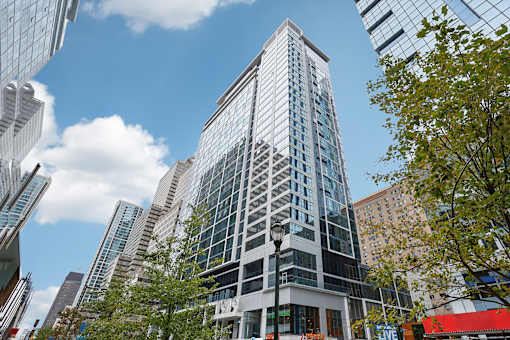A tall building with many windows stands in front of other buildings.