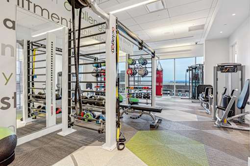 A gym with a variety of equipment including a pull up bar, weights and a bench.