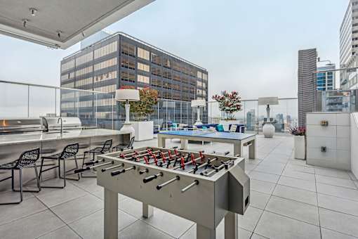 A foosball table is on a rooftop patio with chairs around it.