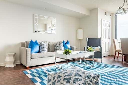 A living room with a white couch, a coffee table, and a blue rug.