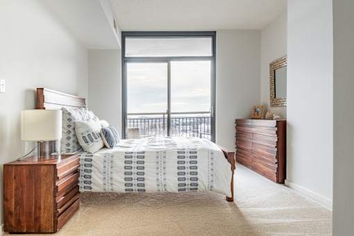 A bedroom with a bed, nightstand, and a window overlooking the ocean.