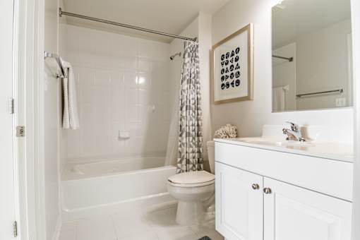 A white bathroom with a toilet, sink, and shower.