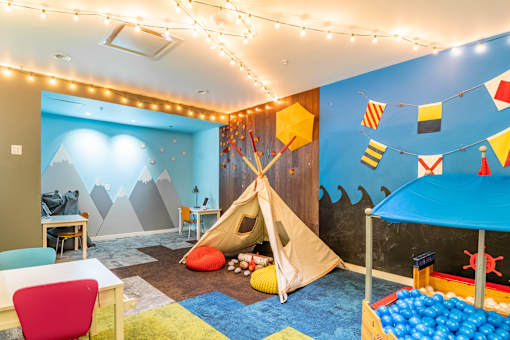 A playroom with a teepee, a tent, and a slide.