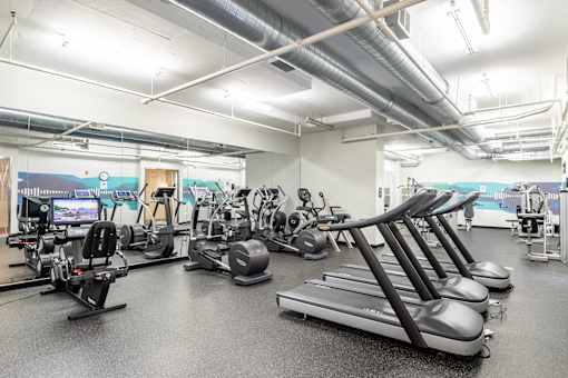 A gym with treadmills, elliptical machines, and other exercise equipment.