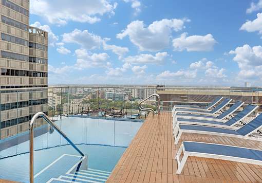 A rooftop pool with lounge chairs and a view of the city.