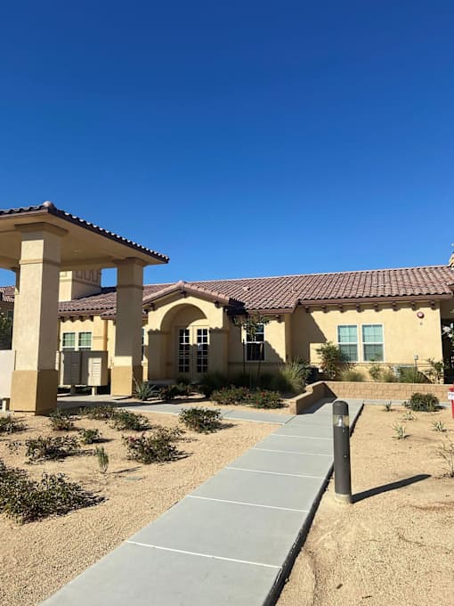 A building with a red tile roof and a covered walkway in front.at The Villas 55+ II Hesperia, Hesperia, CA 92660  