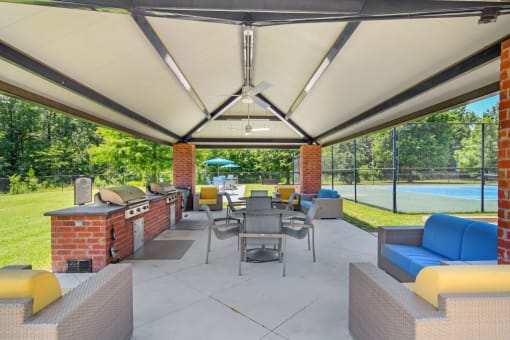 a covered patio with a grill and tables and chairs at The Madison of Tyler Apartment Homes, Tyler