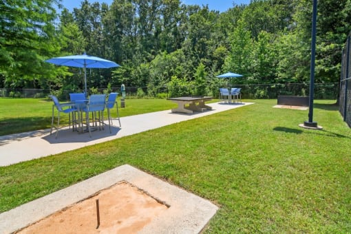 a picnic area with tables and umbrellas in a park at The Madison of Tyler Apartment Homes, Tyler, TX